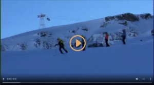 Quatre skieurs en train de descendre une pente enneigée sous un ciel bleu.